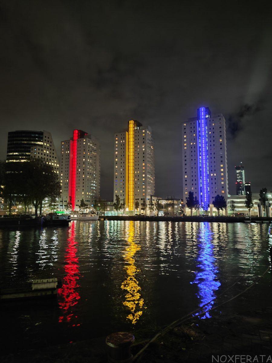 Woontorens Boompjes (Clipper, Schoener, Galjoen) in Rotterdam at night with red, yellow and blue light reflections on the water – Noxferata